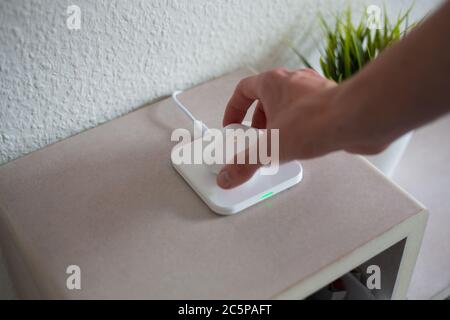 Wireless Headphones being placed or picked up on wireless charging pad to charge battery Stock Photo