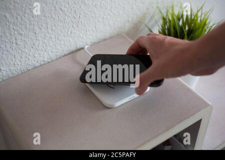 Smartphone being placed on wireless charging pad to charge battery Stock Photo
