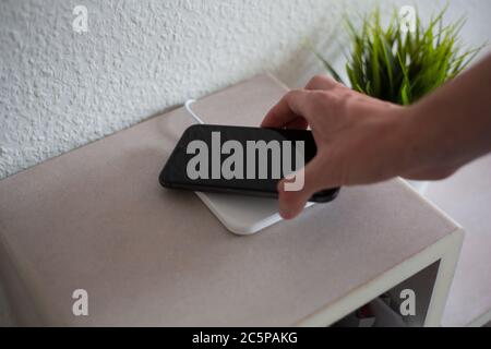 Smartphone being placed on wireless charging pad to charge battery Stock Photo