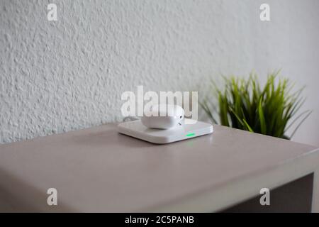 Wireless Headphones being placed on wireless charging pad to charge battery Stock Photo
