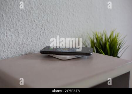 Smartphone on wireless charging pad to charge battery Stock Photo