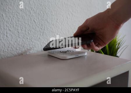 Smartphone being placed on wireless charging pad to charge Stock Photo