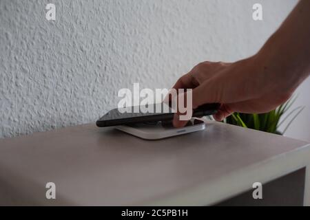 Smartphone being placed on wireless charging pad to charge battery Stock Photo