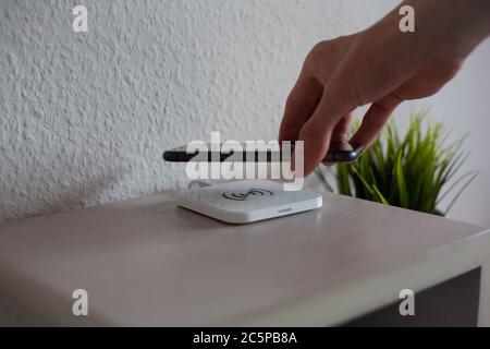 Smartphone being placed on wireless charging pad to charge battery Stock Photo