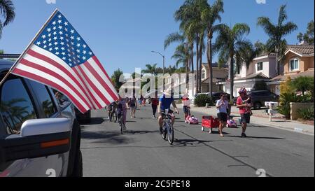 Families participate in a small neighborhood parade celebrating July 4th Stock Photo