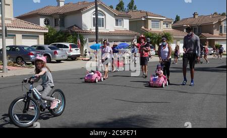 Families participate in a small neighborhood parade celebrating July 4th Stock Photo