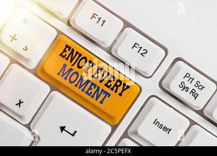 Writing note showing Enjoy Every Moment. Business concept for stay positive thinking for an individualal development Colored keyboard key with accesso Stock Photo