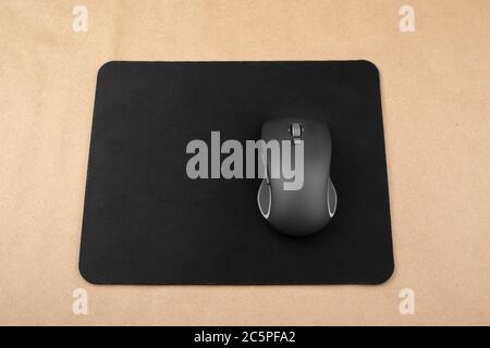 Black wireless mouse on a mouse pad, top view. Stock Photo