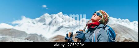 Young hiker backpacker female taking brake in hike walking during high altitude Everest Base Camp (EBC) route with snow Himalayan peaks on background. Stock Photo