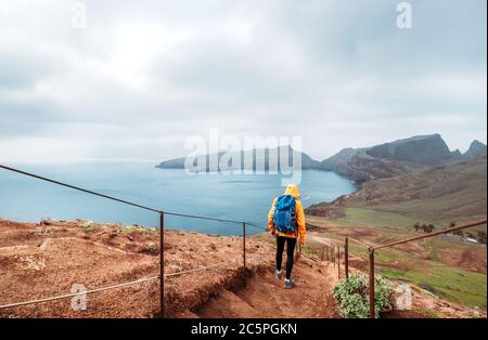 Young male backpacker hiking by footpath on Sao Lourenco headland with Atlantic ocean bay view in the end of February, Madeira island, Portugal. Activ Stock Photo