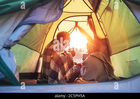 Father and son drink hot tea sitting together in camping tent. Traveling with kids and active people concept image. Stock Photo