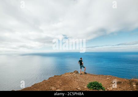 Active traveller man dressed black T-shirt enjoying Atlantic ocean view on the western peninsula point of Madeira island - Ponta Do Pargo, Portugal. Stock Photo