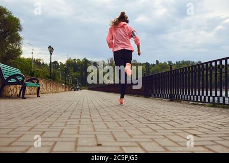 Back view of woman in sportswear running along riverside, copy space. Jogger on training, getting ready for marathon Stock Photo