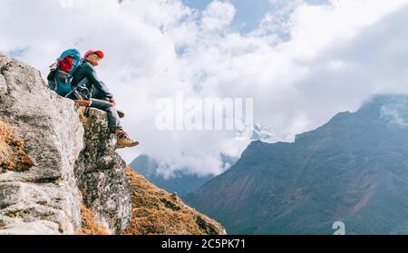 Young hiker backpacker female sitting on cliff edge and enjoying the Imja Khola valley during high altitude Everest Base Camp (EBC) trekking route nea Stock Photo
