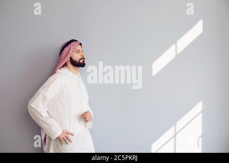 Confident arab man looks up over gray background Stock Photo
