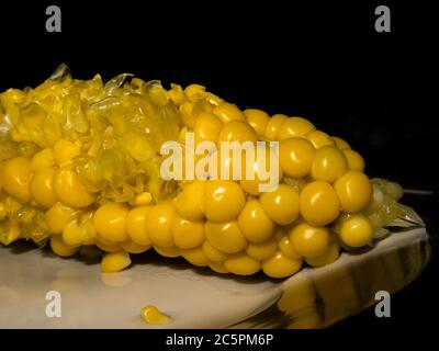 Yellow sweet corn half-eaten. Black background. Close-up picture. High-quality photo Stock Photo