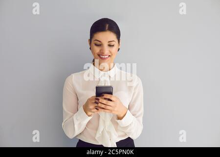 Happy elegant young businesswoman using smartphone on background Stock Photo