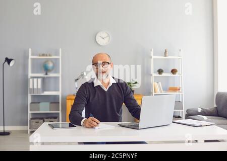 Serious senior man working online on modern netbook at home. Entrepreneur using internet for business conference Stock Photo