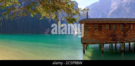 turquoise water and brown wooden building on stilts at the Lago di Braies in Alto Aldige, Italy Stock Photo