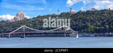 Pedestrian bridge in Kyiv, view panorama of the city of Kyiv, on Dnipro river, sailboat, Ukraine. Stock Photo