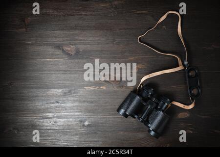 Black military binoculars on wooden background. Lot of copy space for your text. Flat lay. Stock Photo