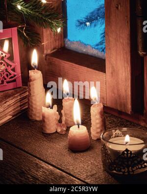 Candles made from beeswax next to a window in winter Stock Photo