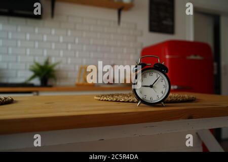 Close up of alarm clock on table in kitchen. Black vintage clock on kitchen table. Stock Photo