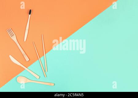 Reusable wooden cutlery and bamboo toothbrush. Eco friendly fork, knife, spoon on a mint orange background. Zero waste concept. Copyspace. Stock Photo