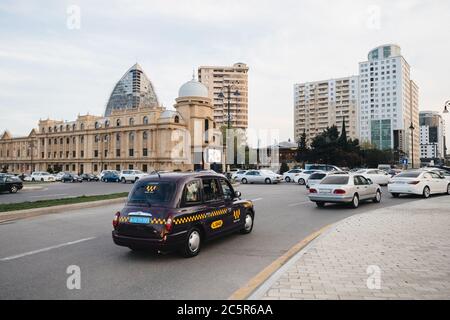 Baku, Azerbaijan - May 2, 2019: Cars driving fast on central Baku driveway with typical Azeri architecture in background Stock Photo