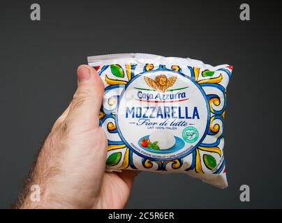 Paris, France - May 26, 2020: Man hand holding against gray background plastic package with Mozzarella Casa Azzurra Fior di latte - delicious Italian food Stock Photo