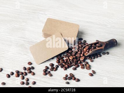 Coffee beans and kraft paper business cards over light wood table background. Stock Photo
