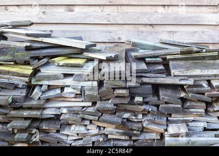 Many old weathered boards stacked against wooden wall Stock Photo