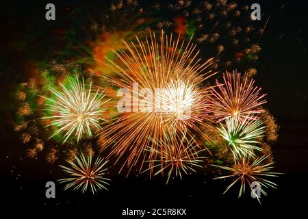 Bright multi-colored fireworks on a festive night. Beautiful color flashes in the dark sky for a holiday. Stock Photo