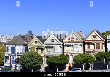 The Painted Ladies from Alamo Square Park.  Downtown San Francisco skyline and Transamerica Pyramid can be seen behind the victorian era houses. Stock Photo