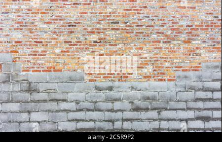 Combination grey cinder block and traditional red and orange brick wall. Stock Photo