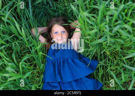 Beautiful little girl runs in the summer field