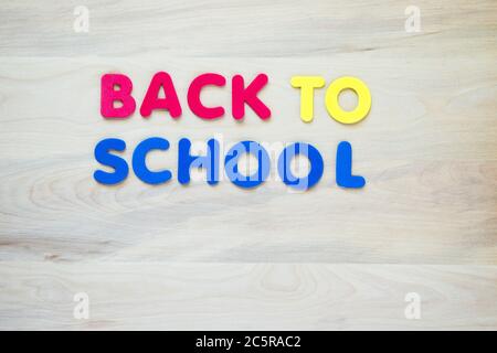 red, yellow and blue foam  letters spelling "Back to School" on a wood background with copy space Stock Photo
