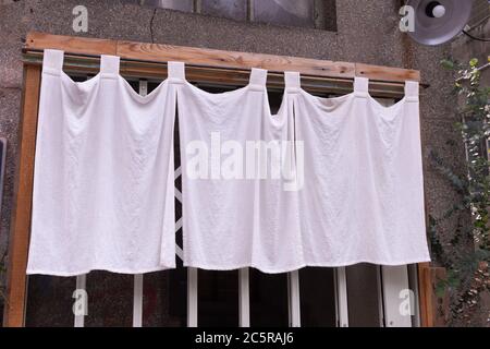 The curtain-like fabric that hangs in front of traditional Japanese restaurants and shops not only serves as a signboard, but holds a larger meaning, Stock Photo