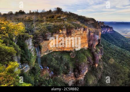 Tall Katoomba fall streaming down to canyon near Three Sisters rock formation in Australian Blue Mountains. Stock Photo