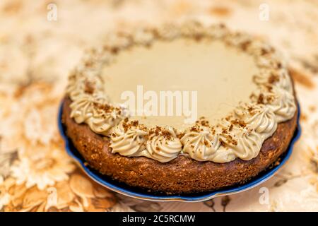 Whole vanilla and caramel chocolate dessert homemade cake with brown frosting and decoration on vintage tablecloth and plate closeup Stock Photo
