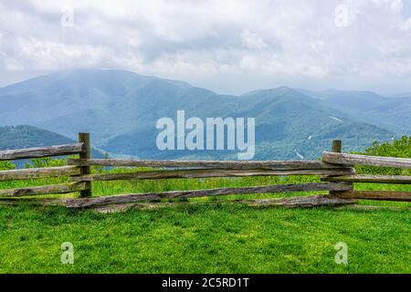 Devil's Knob Overlook green grass field meadow and fence at Wintergreen resort town village near Blue Ridge parkway mountains in summer clouds mist fo Stock Photo