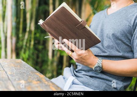 A man hold book and reading in the parks near the river. Stock Photo