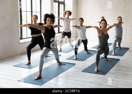 Happy mixed race people standing in warrior II pose. Stock Photo