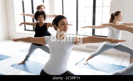 Young fit indian ethnicity woman standing in virabhadrasana second position. Stock Photo