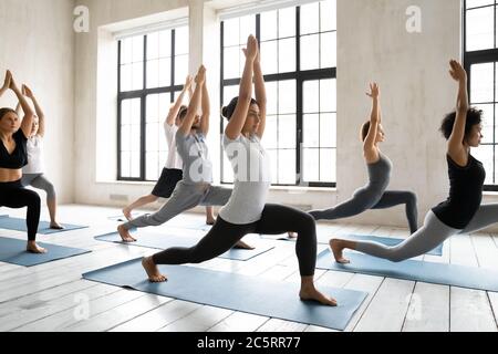 Group of diverse students practicing warrior 1 exercise on yoga class. Stock Photo