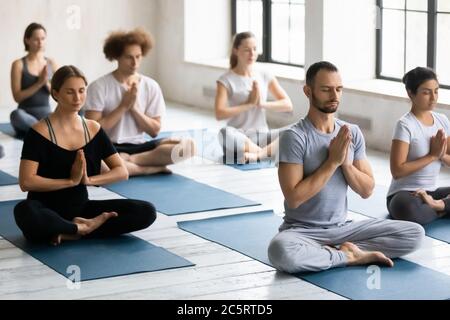 Young motivated multiracial people enjoying meditating with closed eyes. Stock Photo