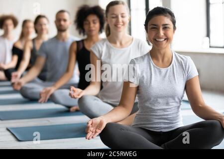 Happy young pretty indian ethnicity woman sitting in lotus pose. Stock Photo