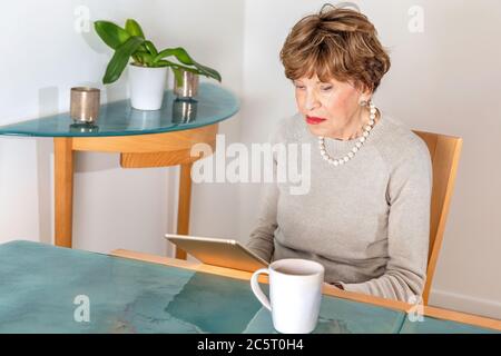 EIghty year old elegant woman reading her ipad Stock Photo