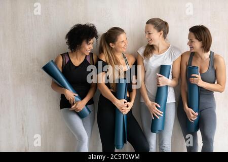 Happy four attractive young multiracial female friends enjoying chatting indoors. Stock Photo