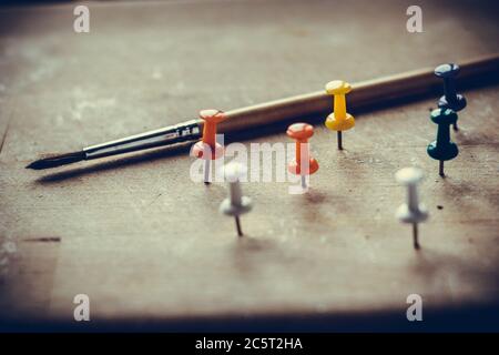 Paper buttons stuck in a wooden Board and an art brush. Conceptual still life Stock Photo